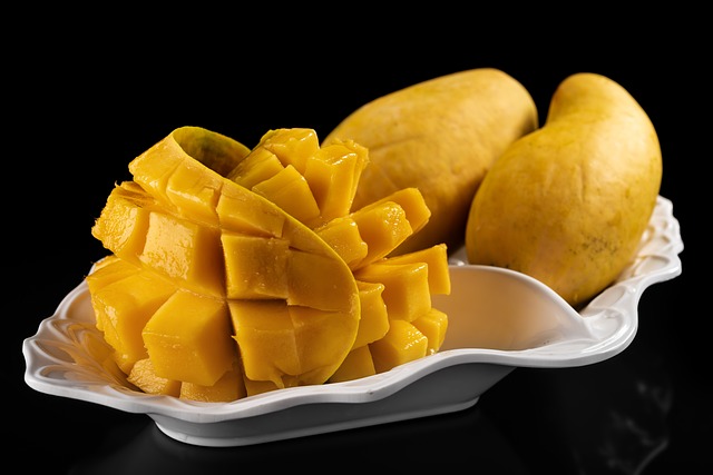 Mango fruit and its slice on a white plate