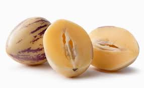 A pepino melon cut open to reveal its creamy interior, with two halves displayed alongside a whole fruit featuring purple stripes