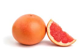 A whole grapefruit and a slice of pamelo fruit against a white background.