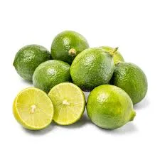 A pile of small, round calamansi fruits with green, slightly bumpy skin, including two fruits cut in half to reveal their juicy, light green interiors, placed on a light-colored surface.