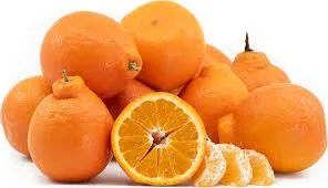 A pile of bright orange citrus fruits, Tangelo, with one fruit cut in half to reveal the juicy interior and a few slices beside it, all set against a plain white background.