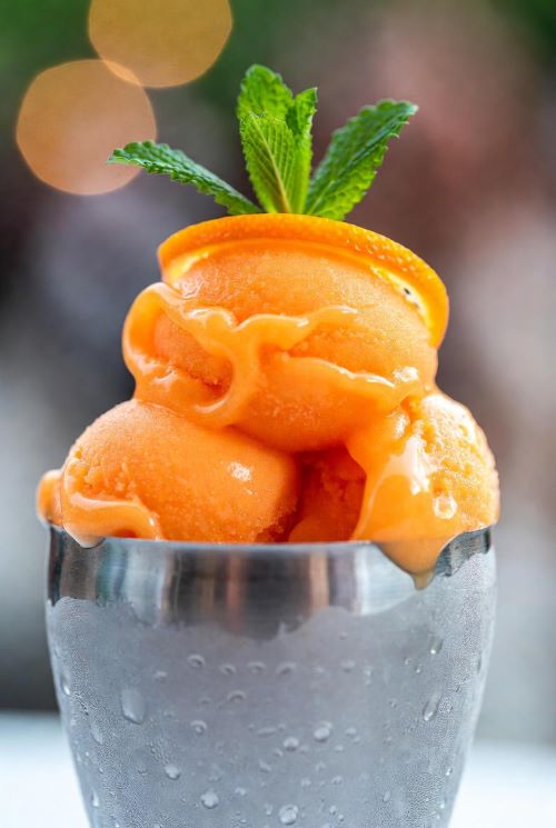 Smooth and creamy 3-ingredient citrus sorbet made from fresh orange juice, served in a frosted cup with an orange zest curl and mint leaf.