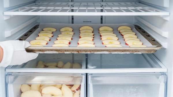Flash freezing apple slices on a parchment-lined baking sheet